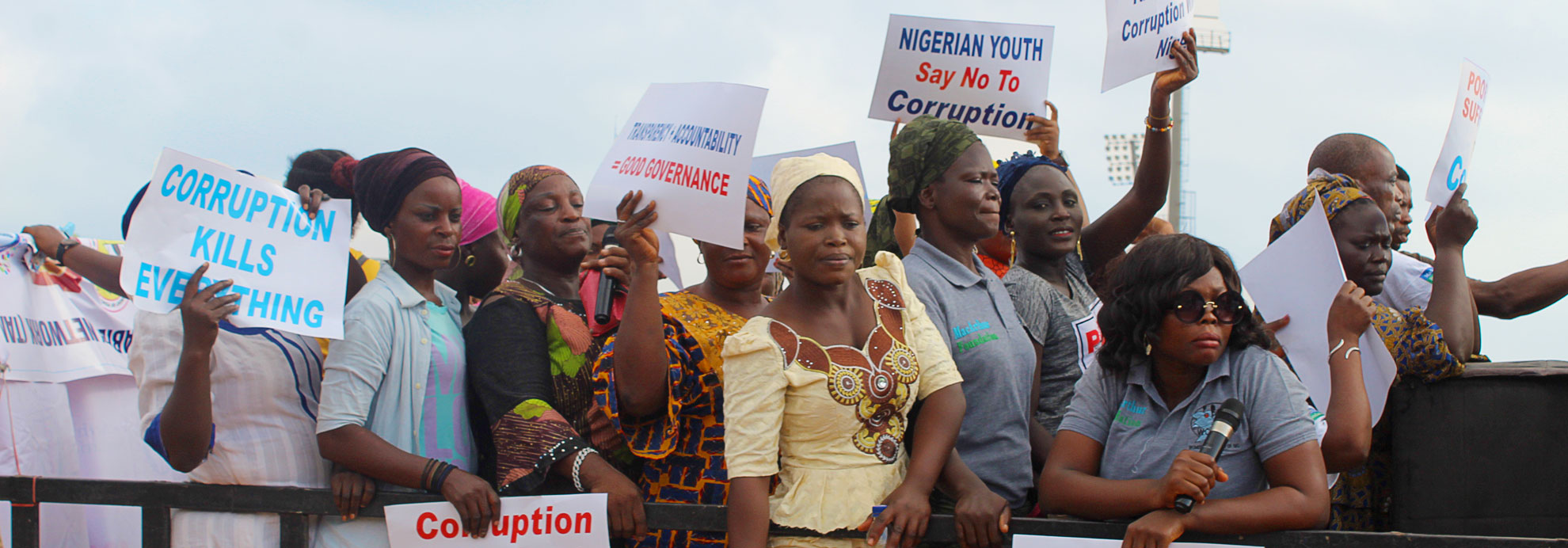 A group of people at a protest holding signs against corruption.